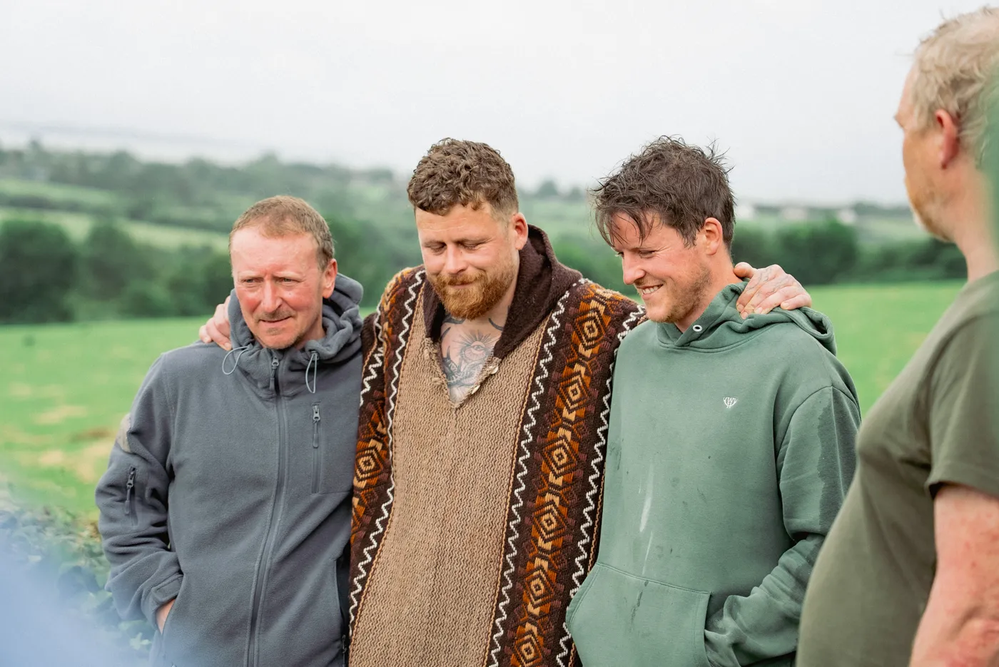 Three men standing together in a field